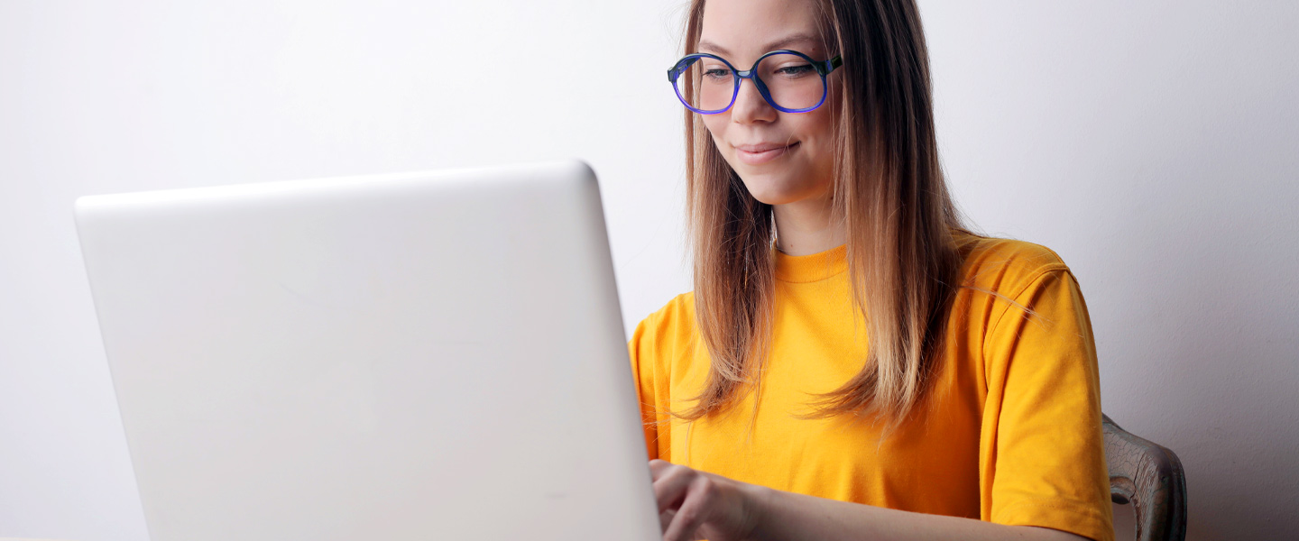 Frau mit Brille sitzt am Laptop