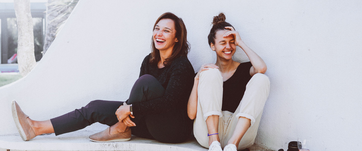 Zwei Frauen sitzen auf dem Boden und lachen