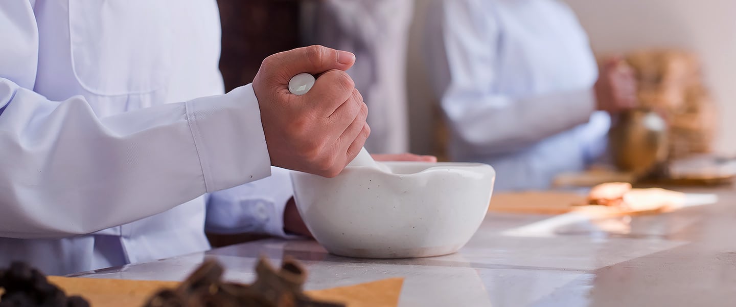 Chinesische Medizin. Kräuter werden mit Mörser und Stößel zerkleinert.