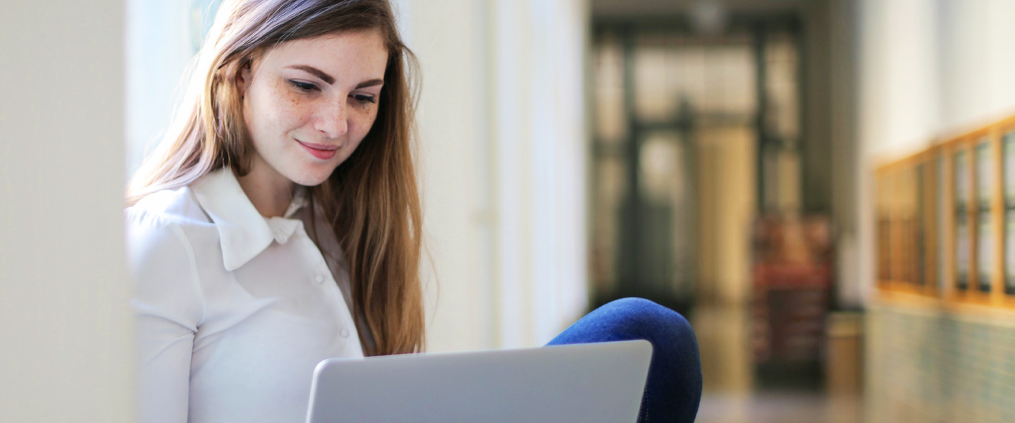 Junge Frau schaut prüfend auf ihren Laptop.